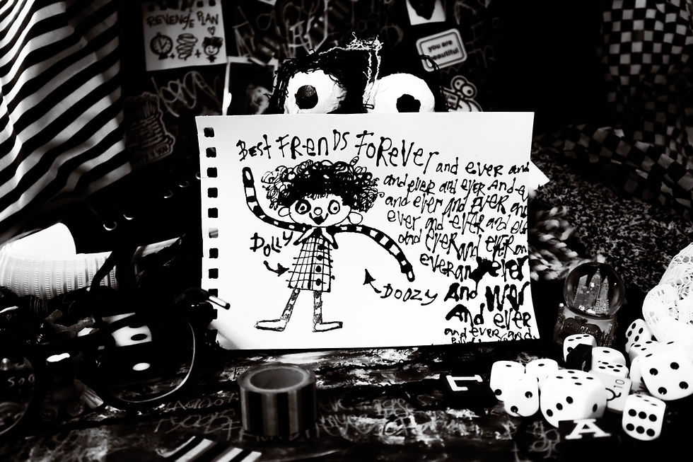 Black-and-white still life of a doodled card reading Best Friends Forever, surrounded by dice, stripes, and playful clutter. Minnesota Fringe Production.