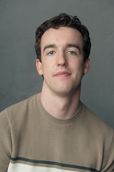 Portrait of a young man in a beige striped sweater against a gray background, looking at the camera with a neutral expression. Edinburgh Fringe artist Peter McCormick