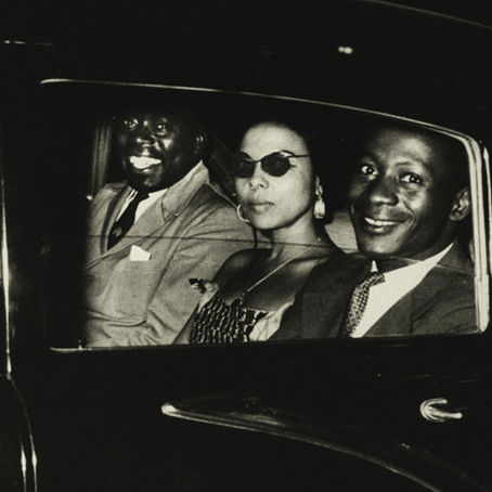Soundtrack to a coup d'état. Dans une voiture, trois personnes sont assises à l'arrière, regardant la caméra.