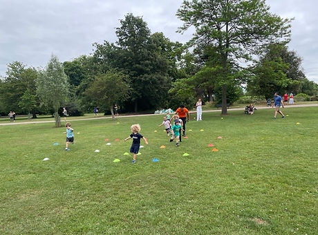 Children moving around cones in a field