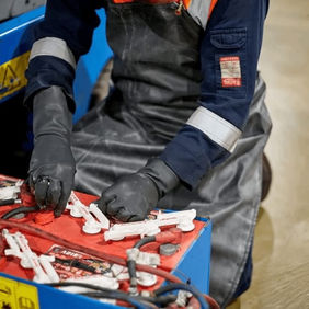 Technician in protective gear working on a large battery