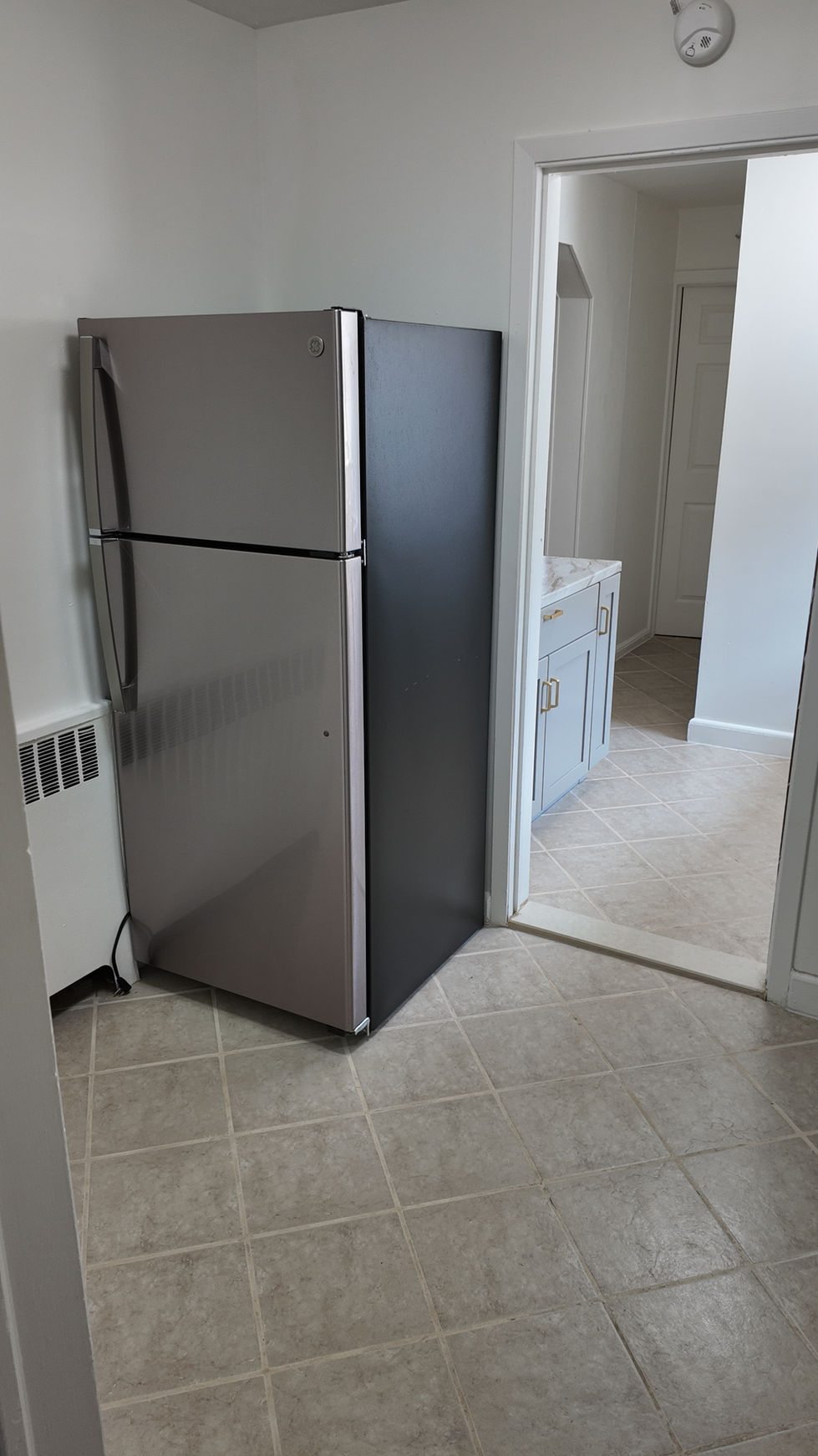 Diagonal tile flooring surrounding a stainless refrigerator