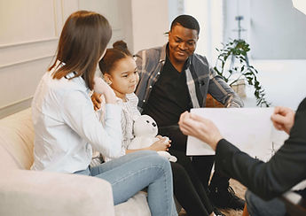 A family sitting on a couch listening while their little girl speaks