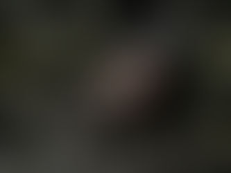 Yüzü çamur ve yaralarla kaplı, sakallı bir adam eski taş kalıntıları arasında yere gömülü şekilde yatıyor. Karanlık ve dramatik atmosferde çekilmiş sinematik bir sahne.