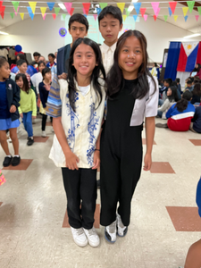 Close-up of a St. Victor student in vibrant embroidered clothing and a patterned headscarf, smiling proudly during the Filipino American History Month Assembly.