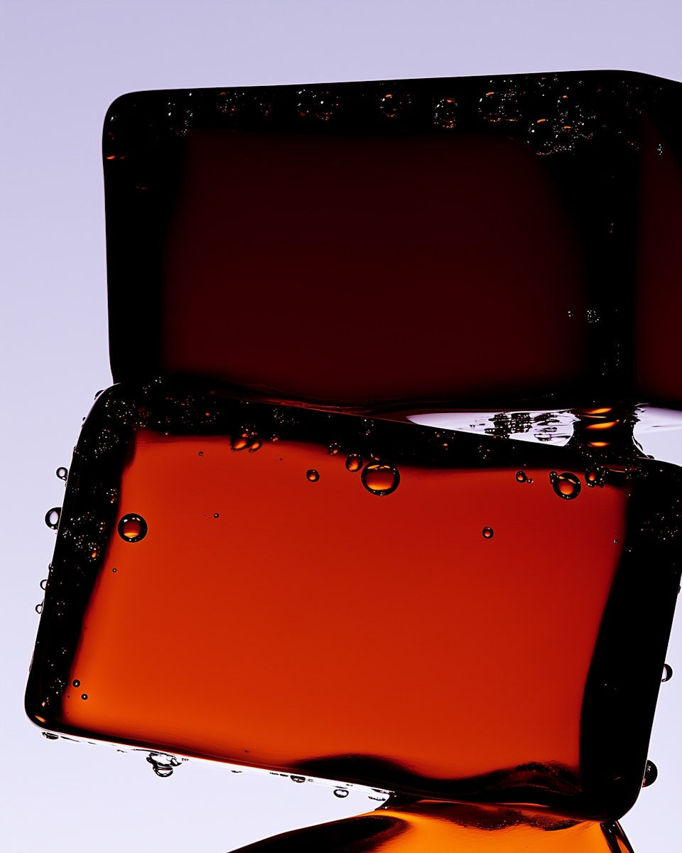 Two dark red ice cubes with bubbles