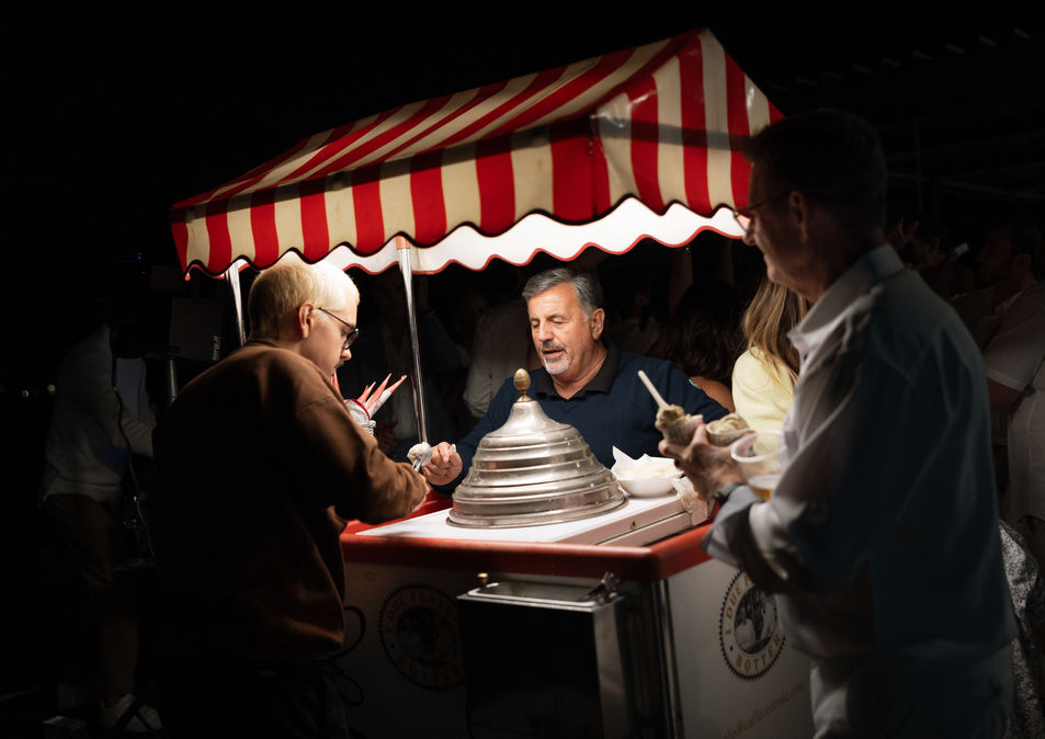 People buying ice cream from a red and white striped cart at night