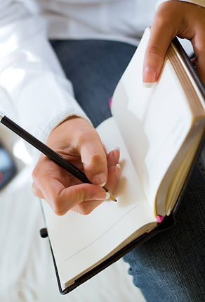 Therapist sitting and writing notes in an open notebook during a session