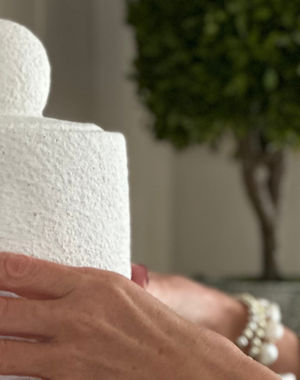 Home decor and accessories for beautiful interiors. White Jar being placed on shelf in living room.