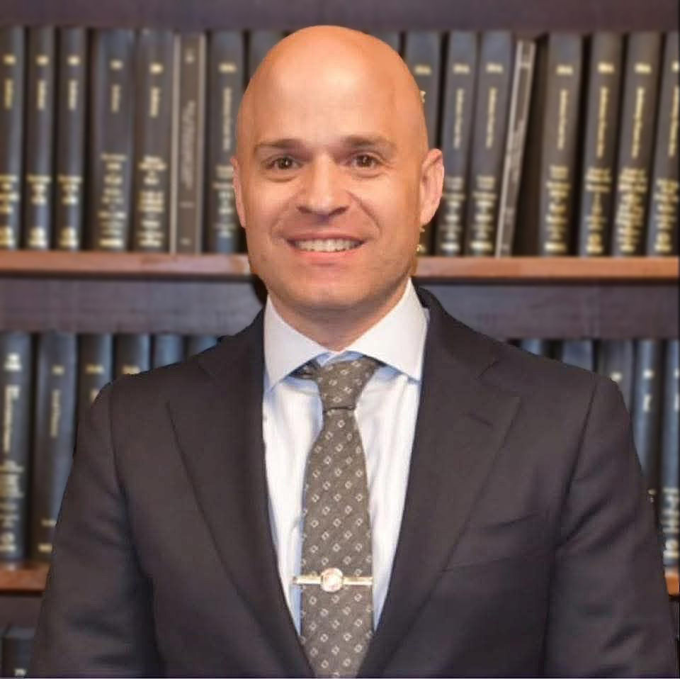 Joe Scianablo, wearing suit, in front of books