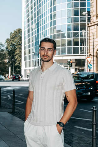 Mann in hellem Polo-Shirt auf Stadtstraße vor Hochhaus.