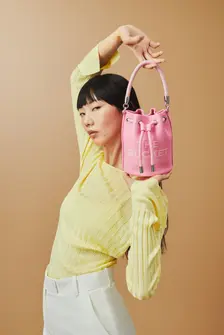 Fashion shoot for Marc Jacobs, captured by fashion photographer Celso Marrero. Model posing with a pink 'The Bucket' bag by Marc Jacobs against a beige background