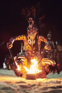 Performer in traditional Mayan attire with fire on the beach during a ritual in Playa del Carmen, Mexico. Captured by lifestyle photographer Celso Marrero.