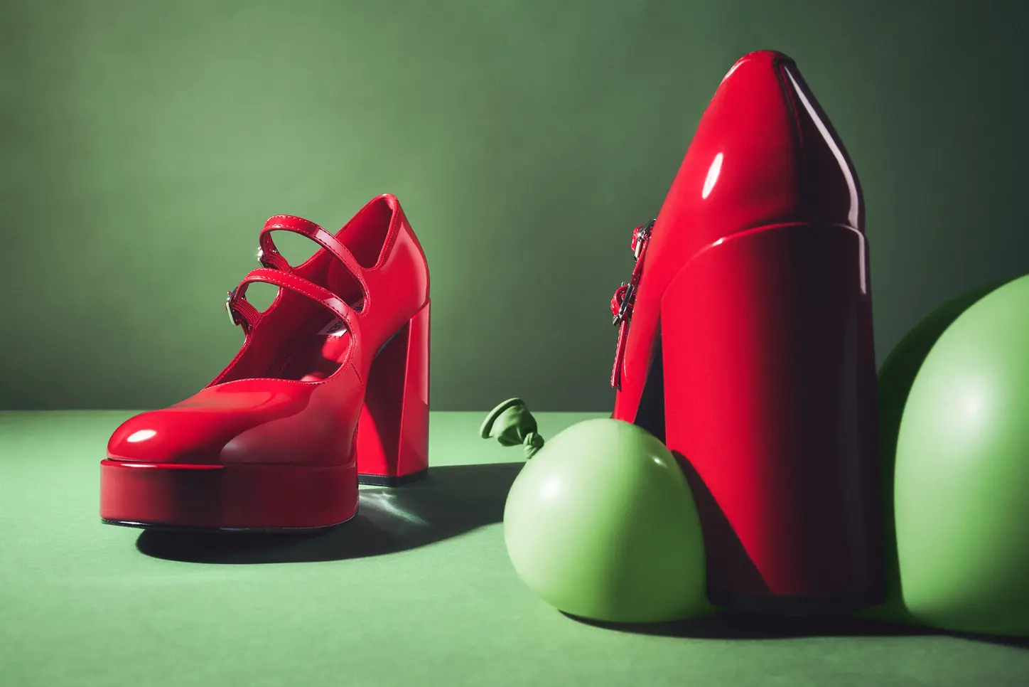 Red Steve Madden heel next to two green balloons, photographed with a focus on the shoe’s details in a creative still life setup by a product photographer in London.