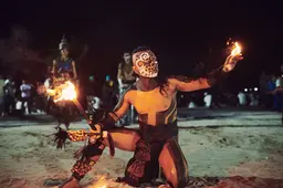 Mayan performer with painted face and traditional attire engaging in a fire ritual in Playa del Carmen, Mexico. Captured by lifestyle photographer Celso Marrero.