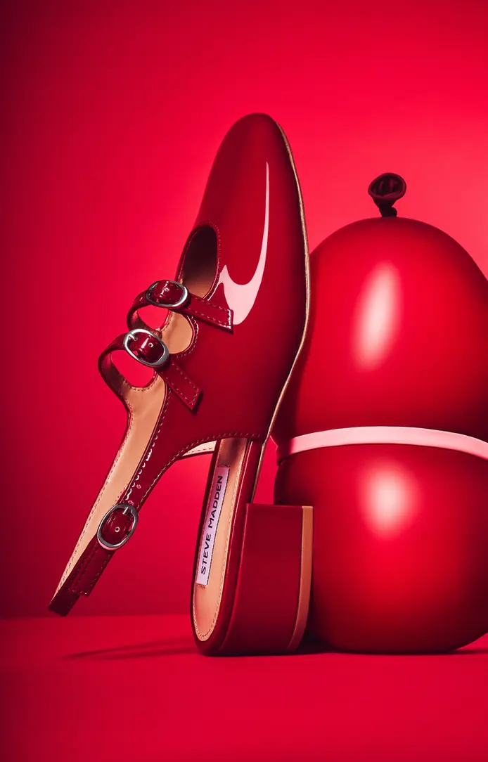 Red Steve Madden high heel with buckle next to a red sphere, captured in a clean, creative still life style by a product photographer in London.