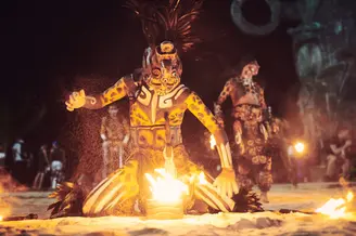 Performer with face paint and traditional Mayan attire performing with fire during a ritual in Playa del Carmen, Mexico. Captured by lifestyle photographer Celso Marrero.
