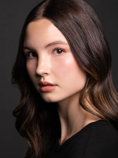 Close-up portrait of a woman with long brown hair wearing black