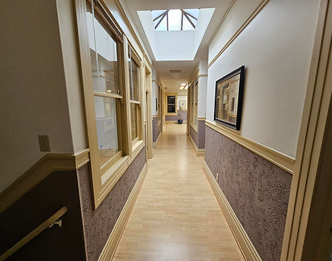 Long hallway with skylight and framed art work on patterned walls.