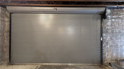 Closed metal roll-up door with number 45, visible on concrete wall