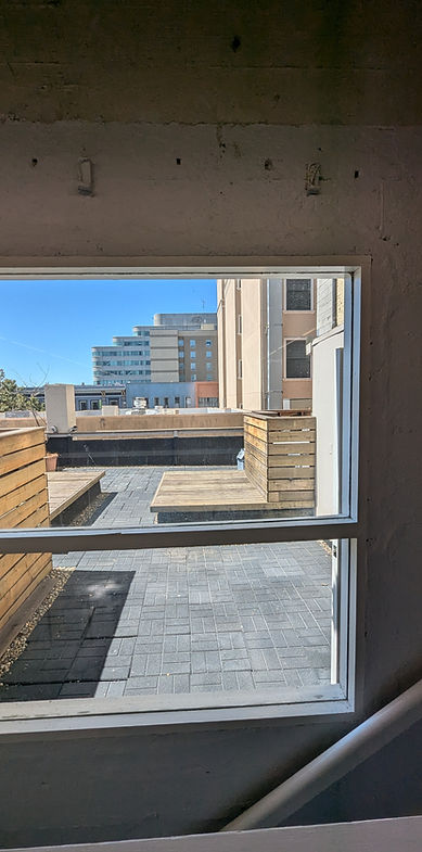 View from a window with a rooftop and buildings in the distance. Oakland