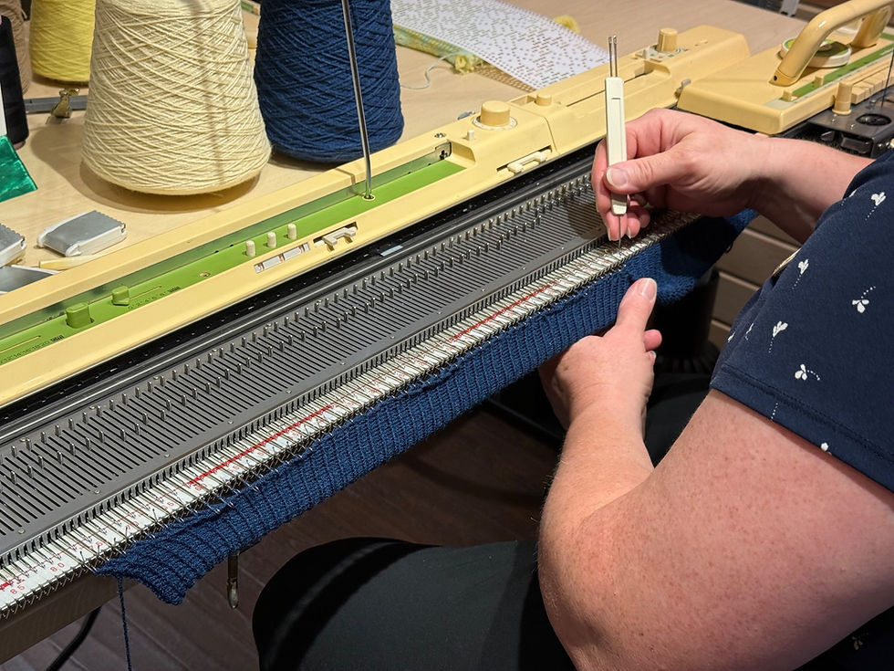 Hands use a transfer tool on navy ribbed knitting