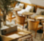 Mobiliario acogedor en una cafetería con sillas de madera y sofás tapizados.