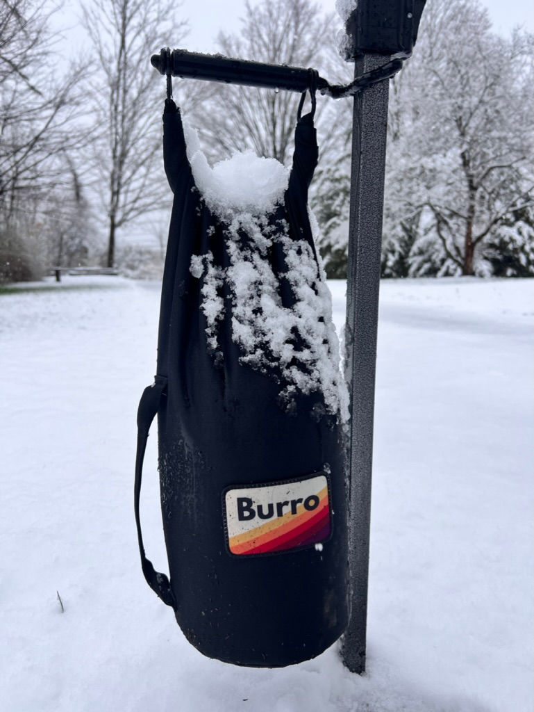 The Burro Tent Weight attached to a tent leg covered in snow.