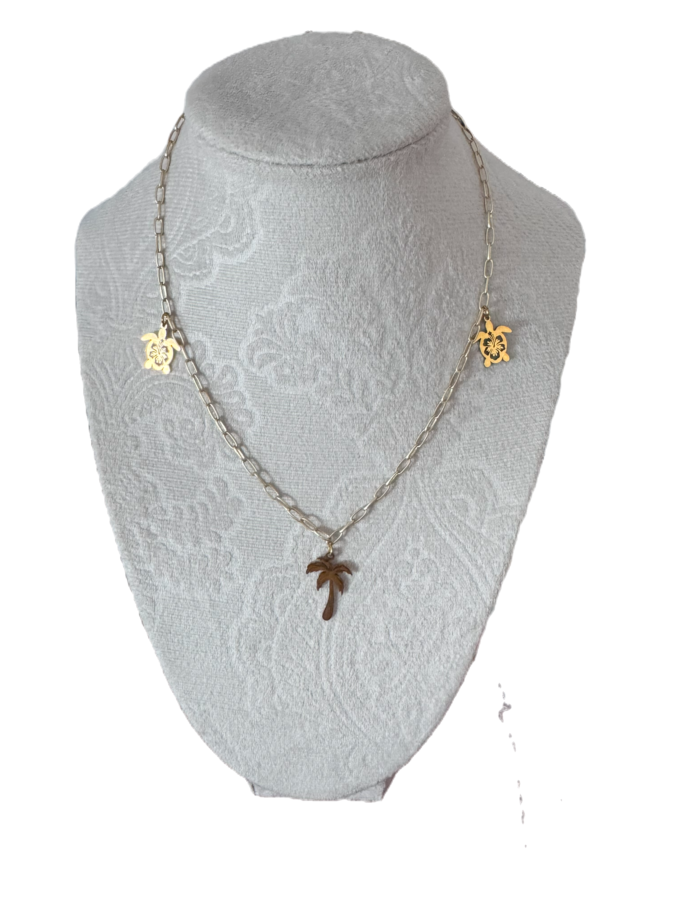 Gold La Palma necklace on white display with palm tree and star charms.