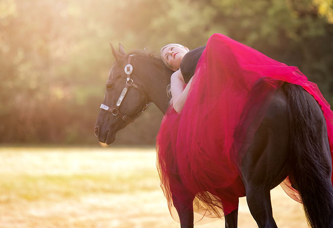 Woman Laying On Black Quarter Horse in Flowy Red Skirt and Black Top