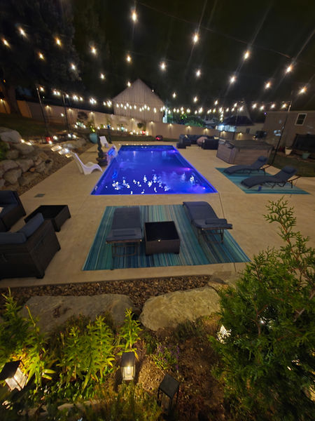 Nighttime view of a pool with glowing lights and outdoor seating