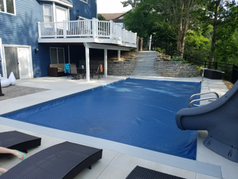 Outdoor swimming pool with slide and covered water, stone path background.