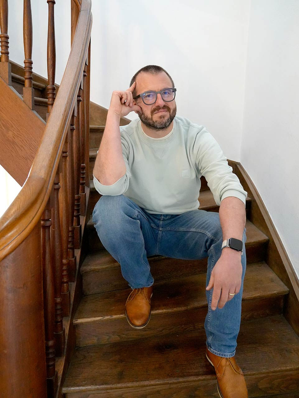 Thomas Grupp, dein Systemischer Coach für München, sitzt entspannt auf einer Holztreppe.