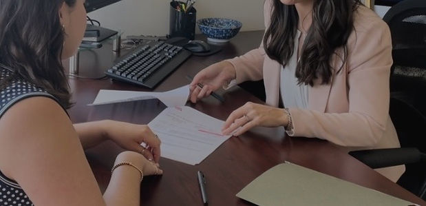 A female lawyer sitting at desk and reviewing contract with female client