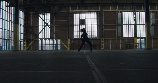 Danseres in loods met snelle dansbeweging – full shot uit brandvideo.