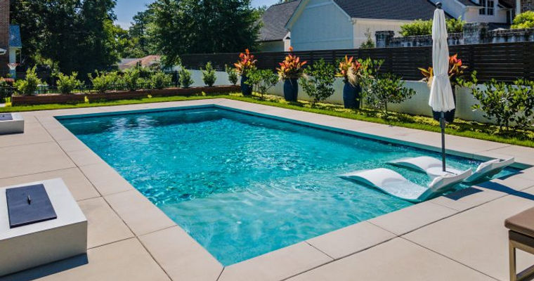 Rectangular pool with shallow end on right side and lawn chairs half-in/half-out of water sitting in shallow end.