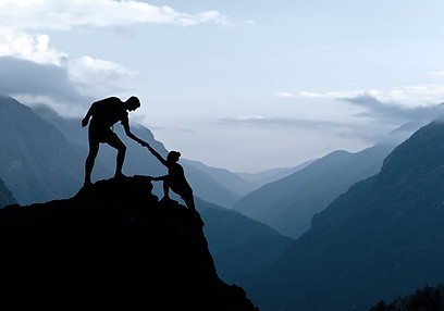 Das Bild eines Bergsteigers, der einem anderen beim Aufstieg hilft