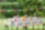 an outdoor party with colourful bunting and a long white table with a cake on it