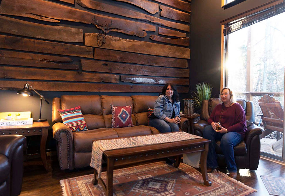 Terri Jestus and her friend sitting within the tiny home, smiling at the camera