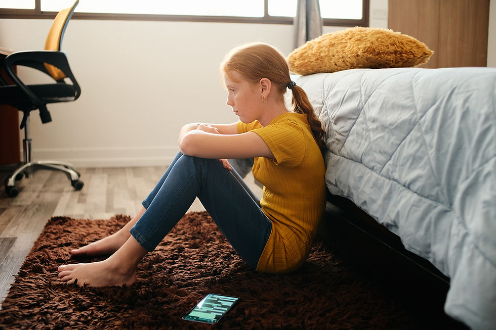 Picture of a girl slumped back beside her bed with a sad expression on her face