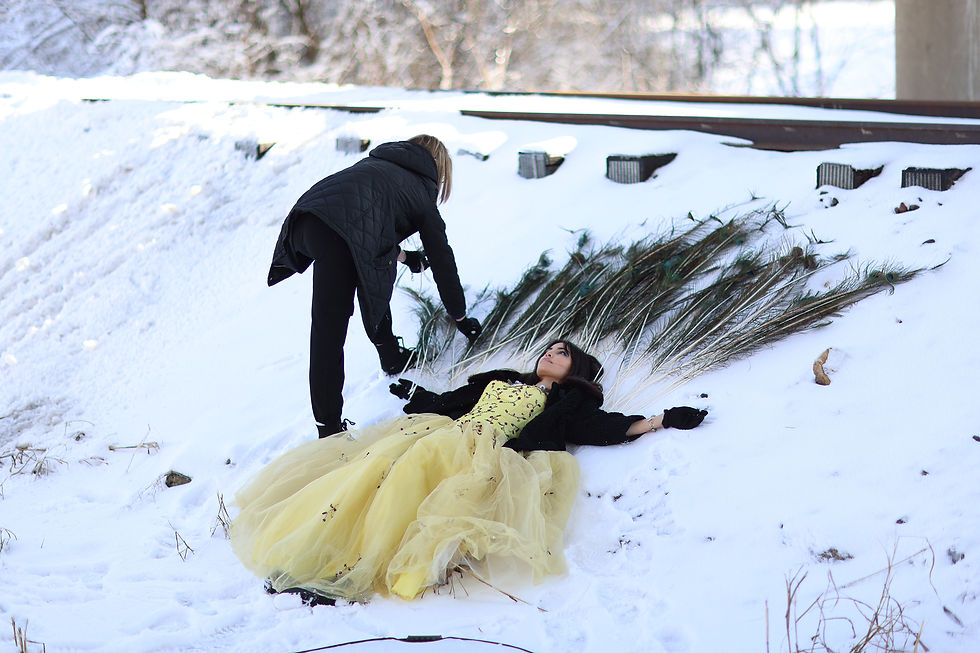 Keeley Hawkins and Hannah Politte in the snow arranging peacock feathers for a 573 Magazine behind the scenes photoshoot in Southeast Missouri