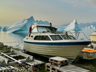 white boat with blue icebergs floating behind it