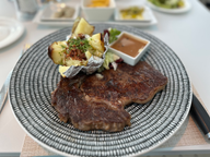 steak and baked potato on black striped plate
