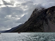 blacks cliffs with small boats in water