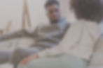 man with gray track suit talking on couch with woman in white sweatshirt