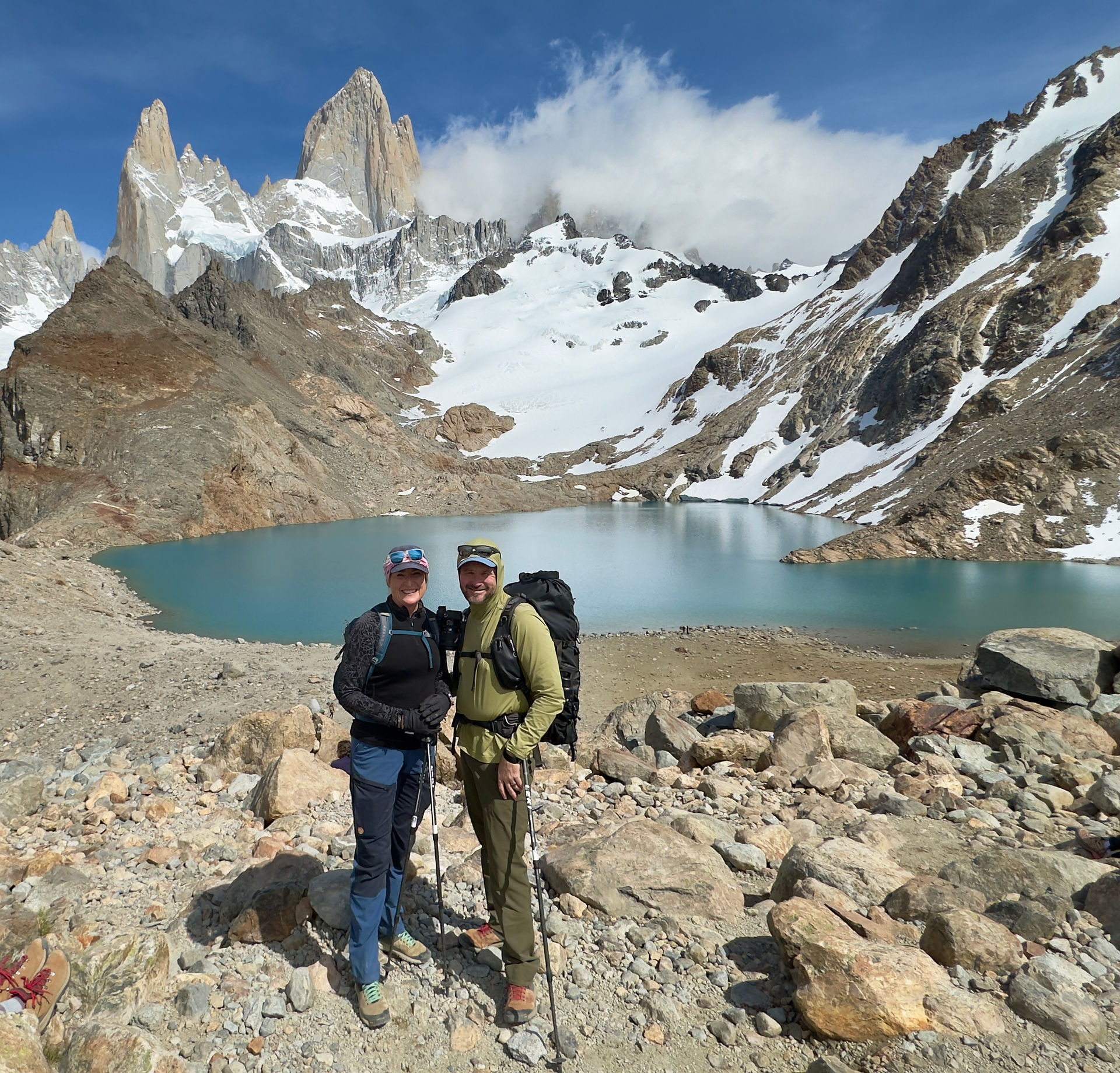 hikers in front of a green lake and mountains