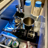 fridge with cans and bottled water and champagne bottle