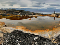multicolored soil around water with cloudy sky