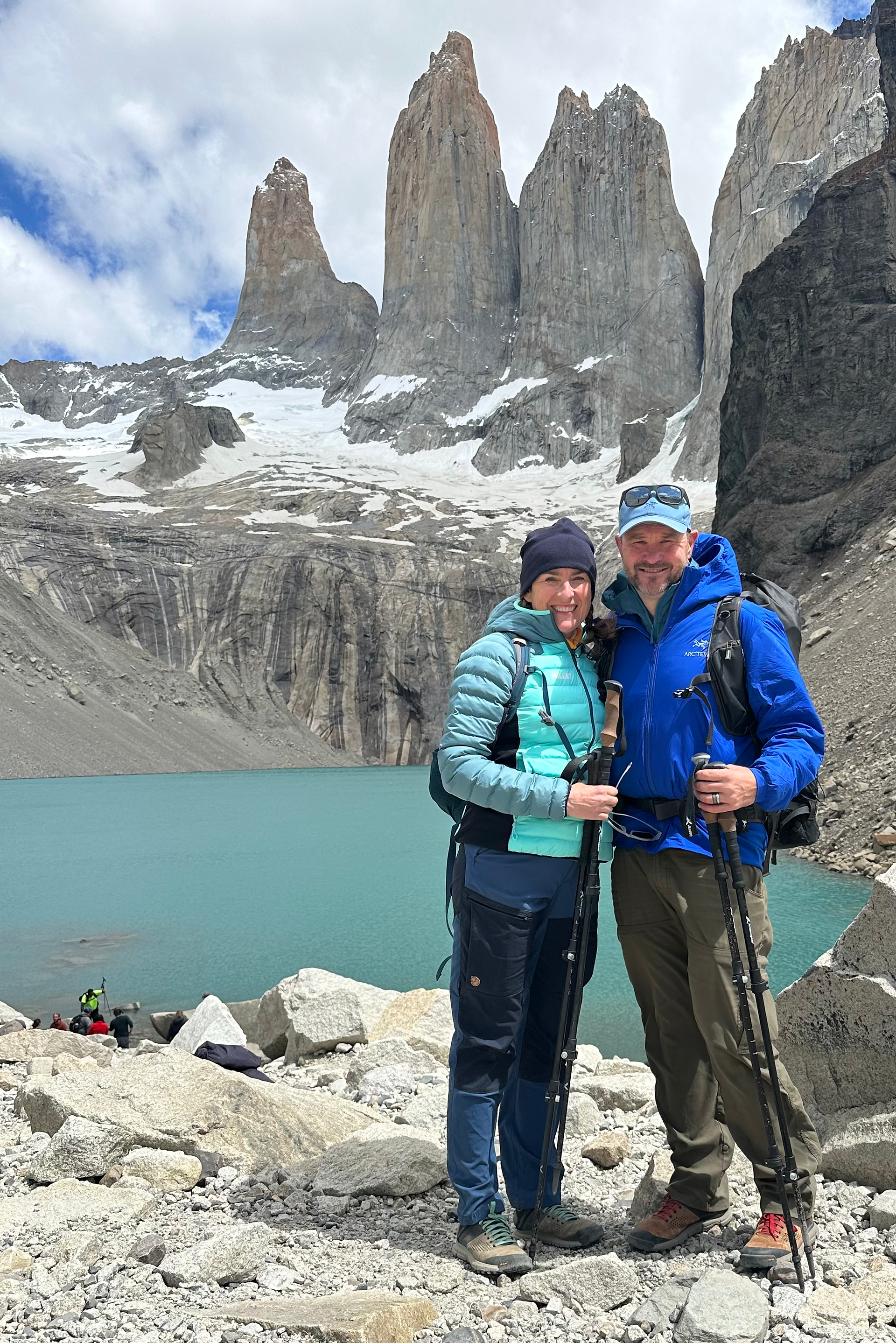 man in blue jacket and woman standing in front of green ake