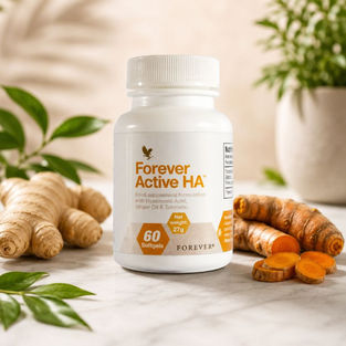 Bottle of Forever Active HA food supplement with hyaluronic acid, ginger oil and turmeric displayed alongside fresh ginger and turmeric on a clean natural background.
